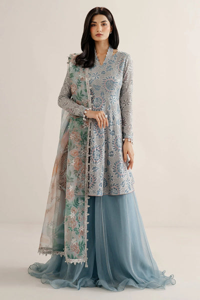 Woman wearing a traditional outfit with embroidered chiffon anarkali top and light blue palazzo pants on a plain background