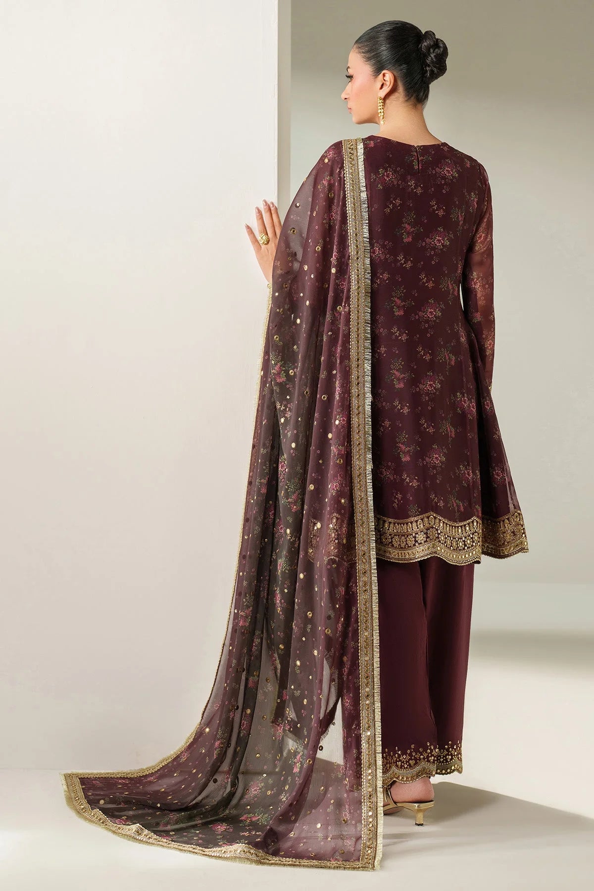 Woman wearing a traditional salwar suit outfit with a long embroidered kameez and matching salwar on a plain background