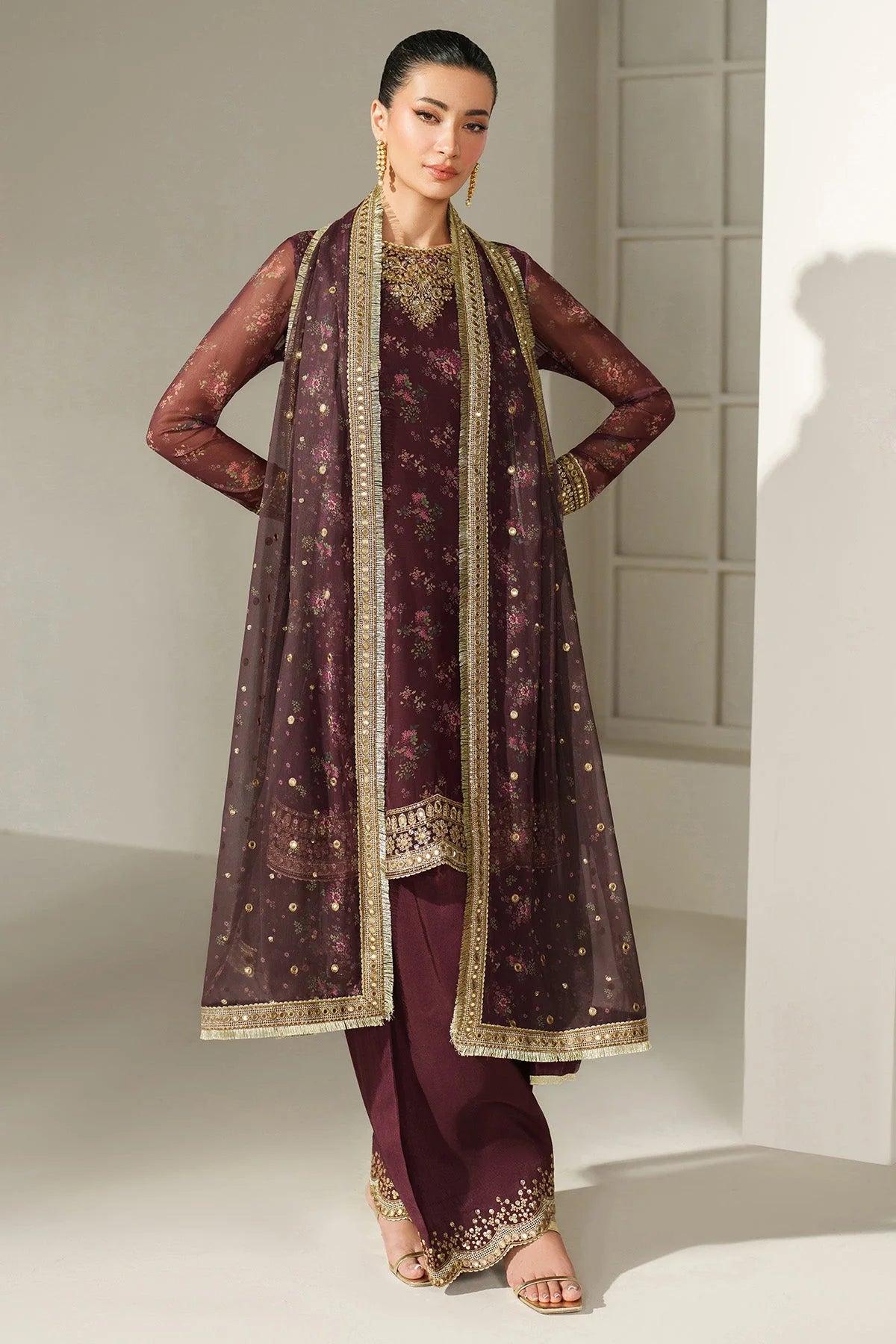 Woman wearing a traditional salwar suit outfit with a long embroidered kameez and matching salwar on a plain background