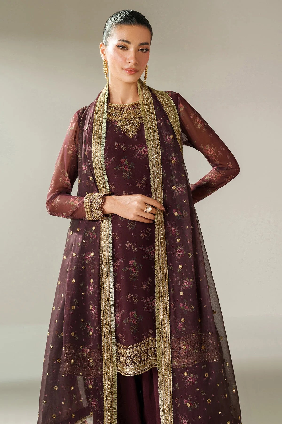 Woman wearing a traditional salwar suit outfit with a long embroidered kameez and matching salwar on a plain background