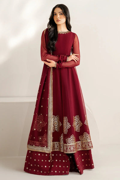 Woman wearing a maroon traditional outfit with gold embroidery on a white background