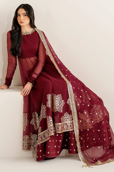 Woman wearing a long maroon anarkali dress with gold embroidery on a white backgroundWoman wearing a long maroon anarkali dress with gold embroidery on a white background