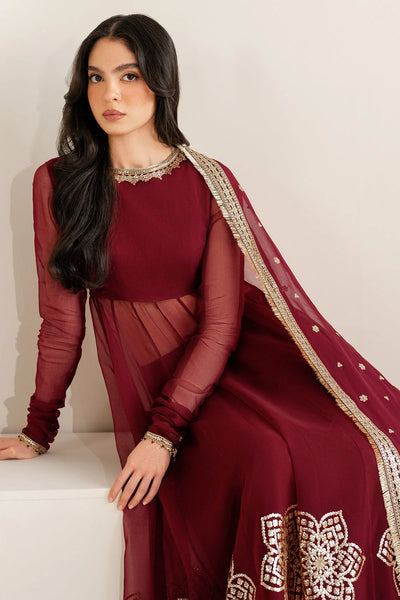 Woman wearing a long maroon anarkali dress with gold embroidery on a white backgroundWoman wearing a long maroon anarkali dress with gold embroidery on a white background