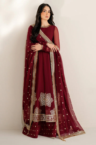 Woman wearing a maroon traditional outfit with intricate patterns on a plain backgroundWoman wearing a maroon traditional outfit with intricate patterns on a plain background