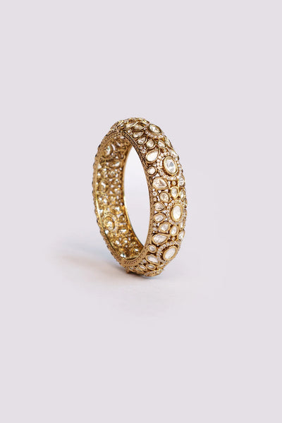 Gold bracelet with intricate design on a light gray backgroundGold bracelet with intricate design on a light gray background