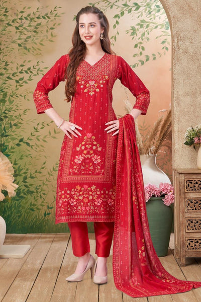 Woman wearing a red embroidered traditional outfit with a matching dupatta in a decorated room.