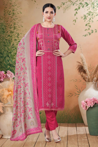 Woman wearing a pink traditional outfit with a floral dupatta against a decorative background.