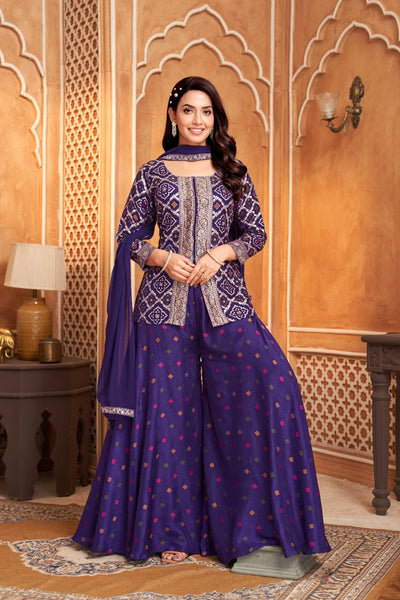 Woman in a traditional purple blue and purple outfit standing in an ornate room.