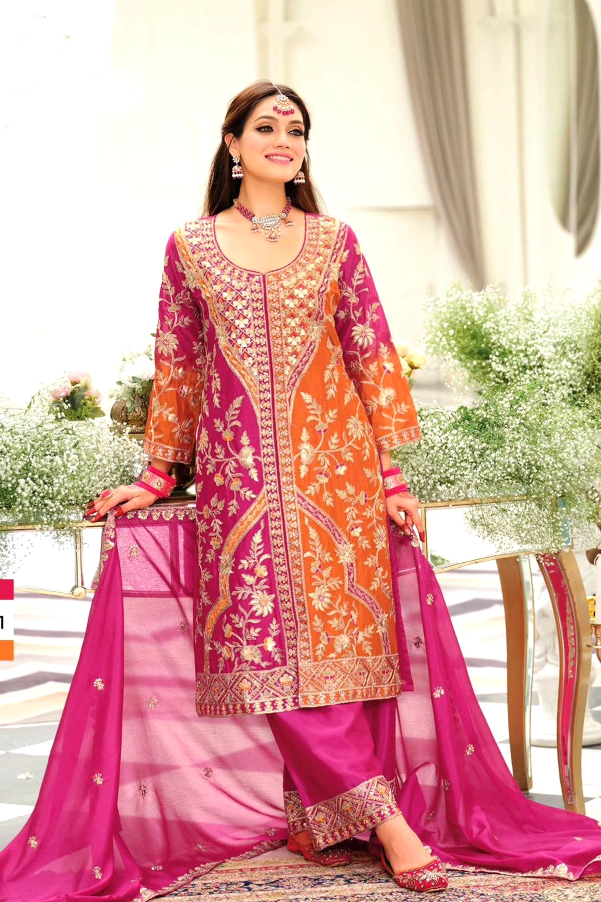 Woman wearing a traditional pink and orange embroidered outfit with a white background