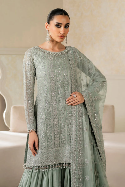 Woman wearing a light green traditional wedding sharara outfit with a matching dupatta in a room.Woman wearing a light green traditional wedding sharara outfit with a matching dupatta in a room.