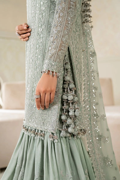 Woman wearing a light green traditional wedding sharara outfit with a matching dupatta in a room.Woman wearing a light green traditional wedding sharara outfit with a matching dupatta in a room.