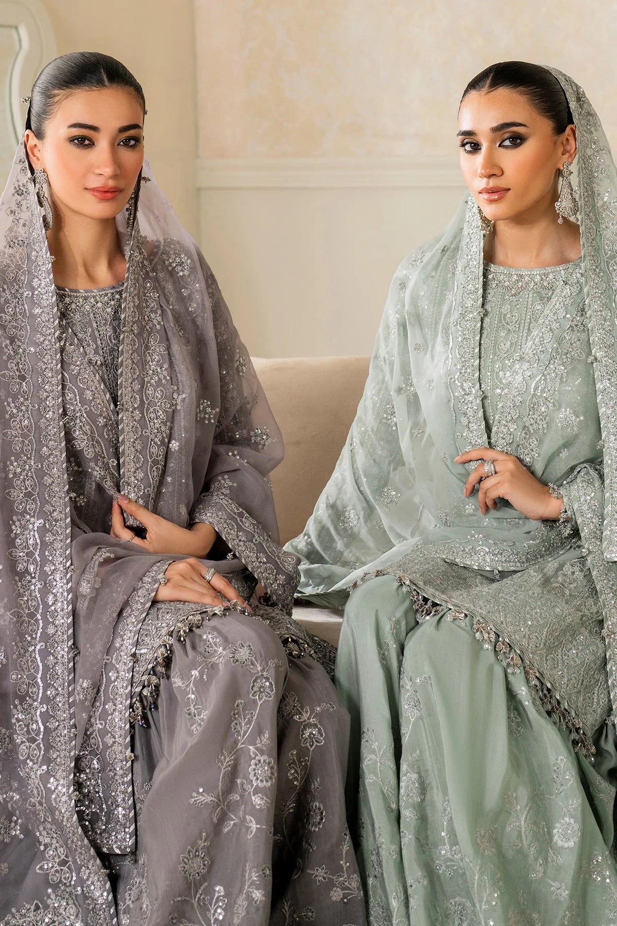 Two women in traditional embroidered outfits sitting on a couch.