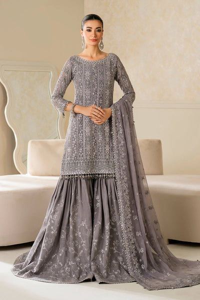 Woman wearing a gray embroidered traditional outfit with a matching dupatta in a room.