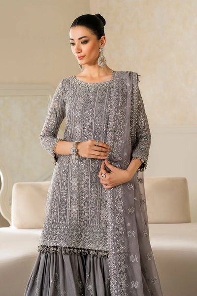 Woman wearing a gray embroidered traditional outfit in a neutral settingWoman wearing a gray embroidered traditional outfit in a neutral setting