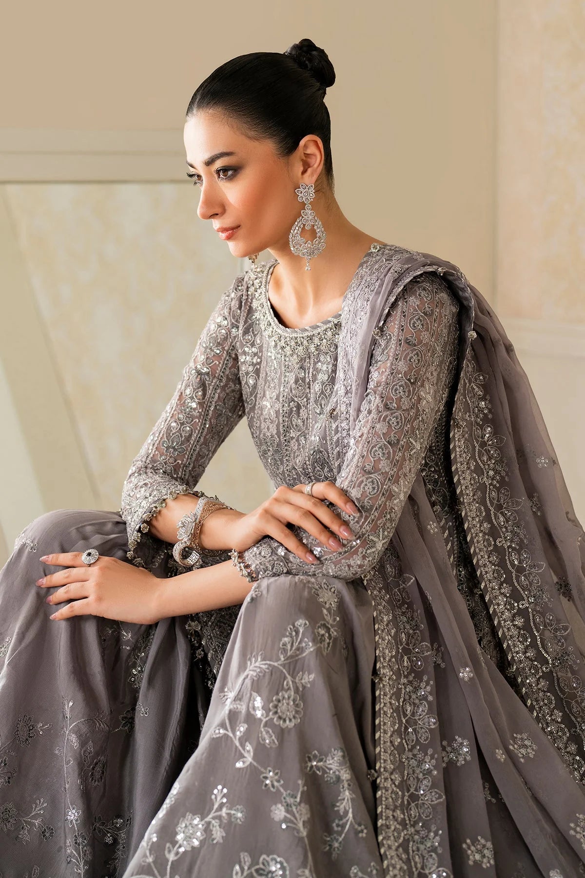 Woman in a gray embroidered traditional outfit with a plain background