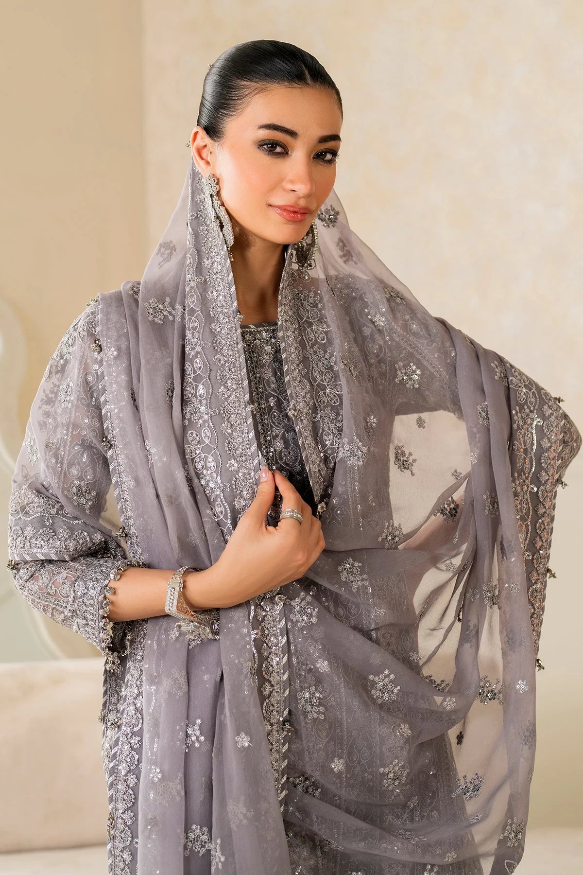Woman wearing a gray embroidered dupatta with a neutral background