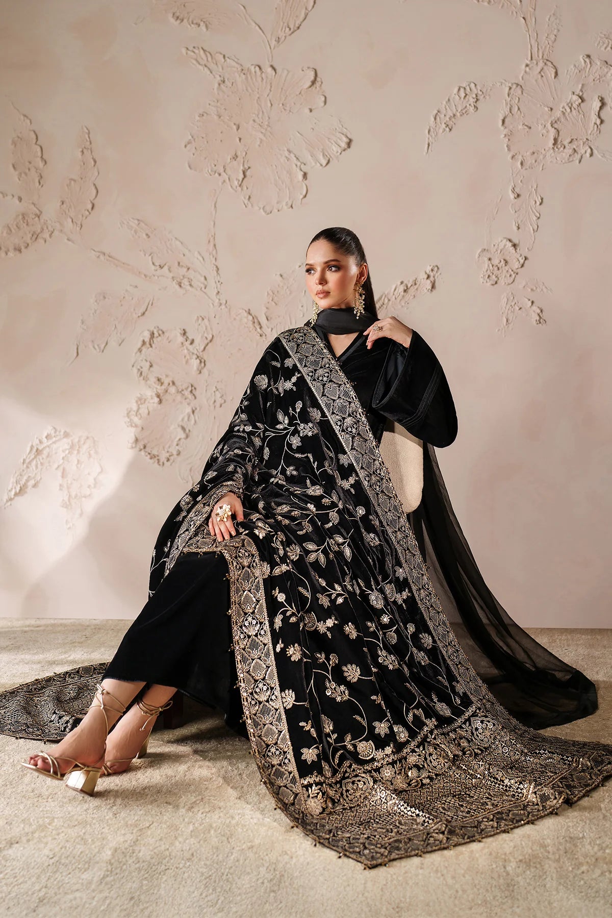 Woman in a black outfit with a large black embroidered velvet shawl 