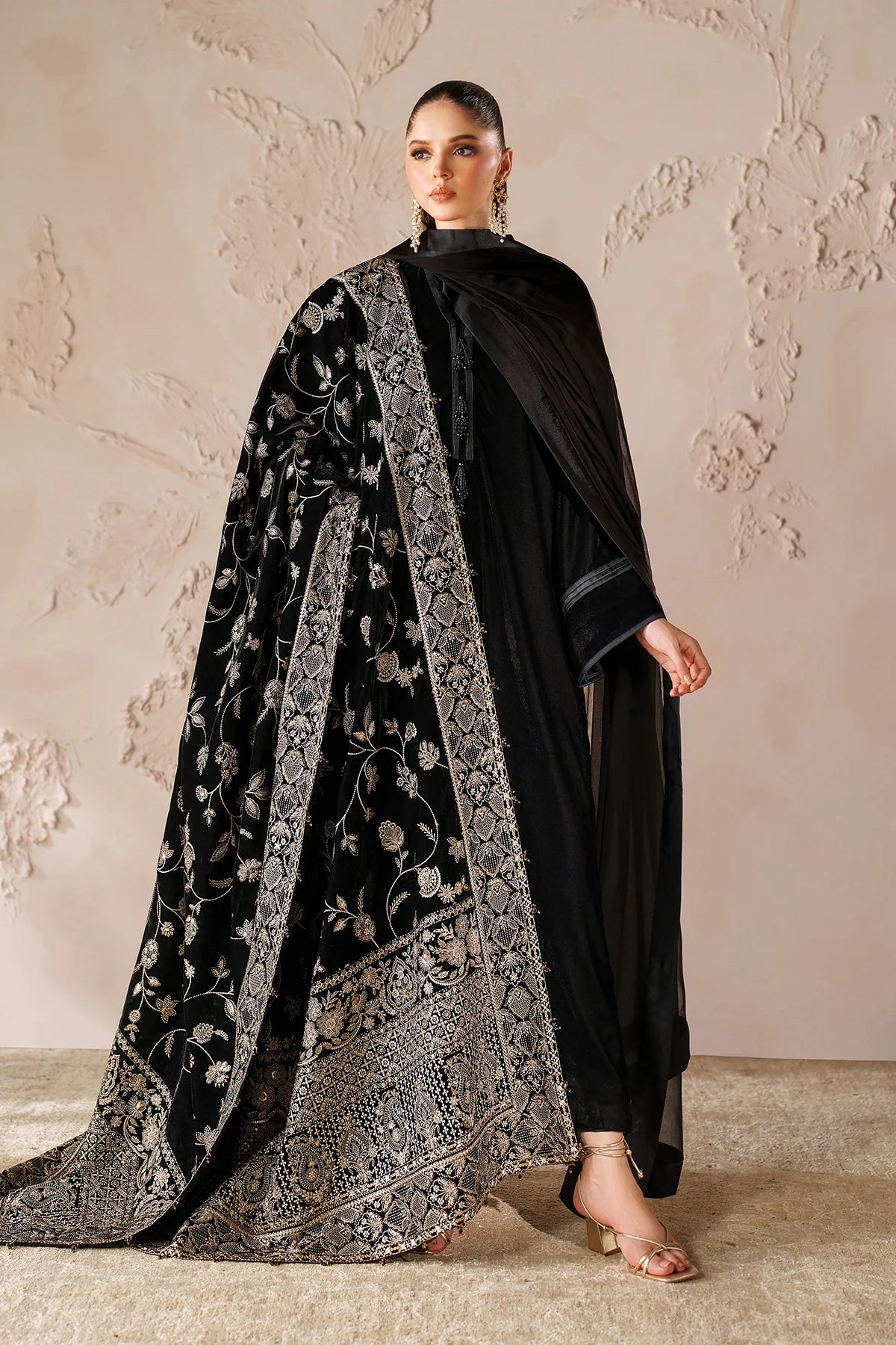 Woman in a black outfit with a large black embroidered velvet shawl 