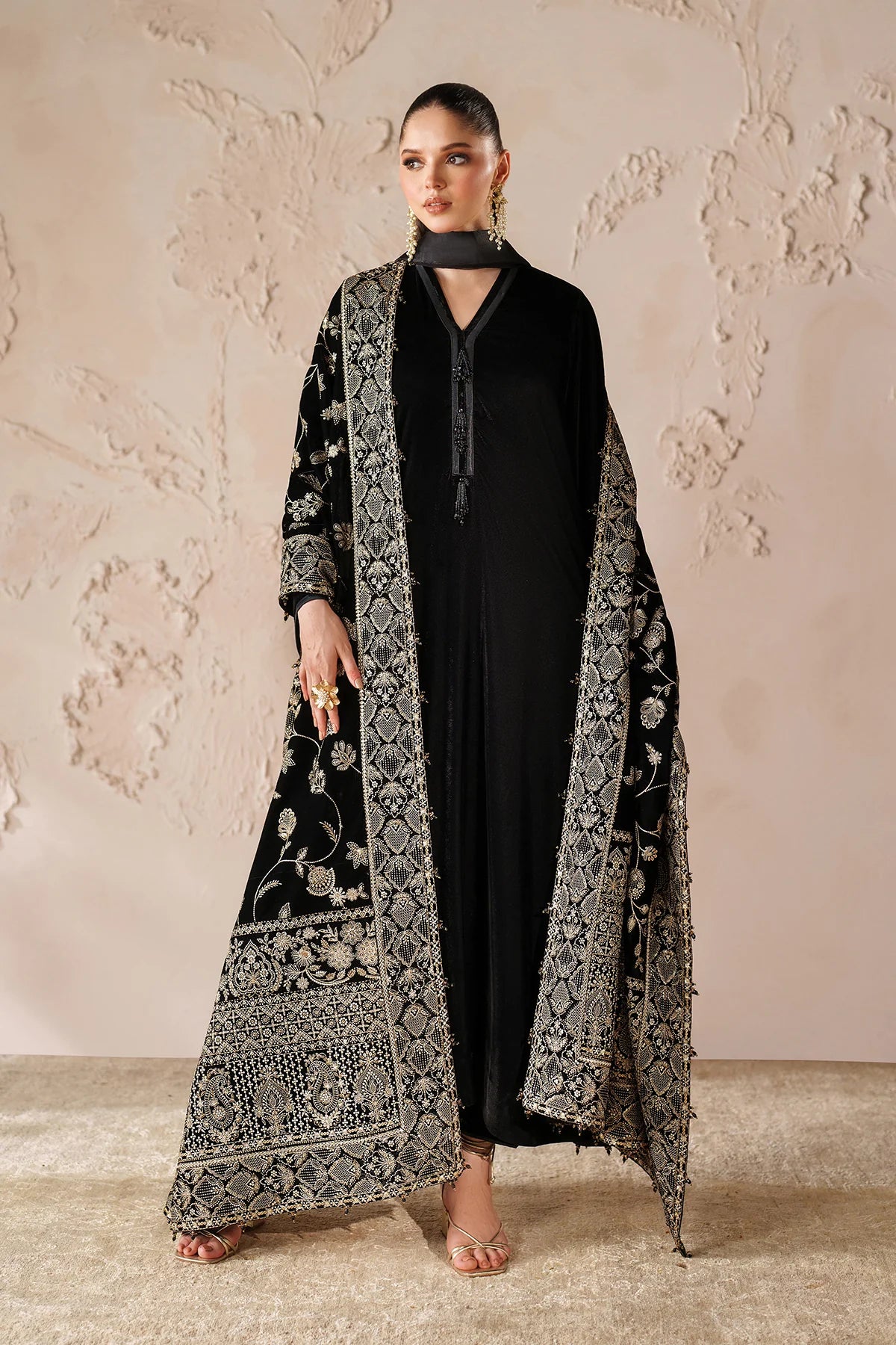Woman in a black outfit with a large black embroidered velvet shawl 