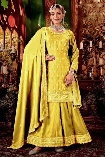 Woman in a yellow traditional sharara outfit with a matching dupatta against a decorative backgroundWoman in a yellow traditional sharara outfit with a matching dupatta against a decorative background