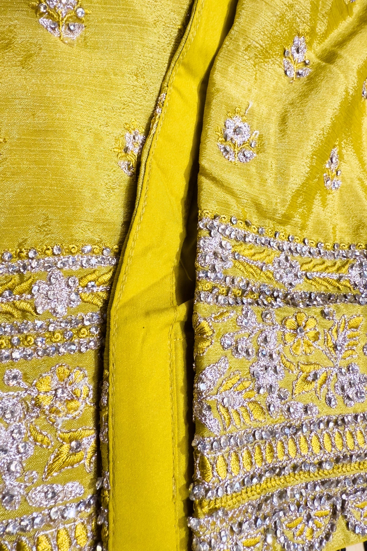 Close-up of a yellow fabric with intricate silver embroidery