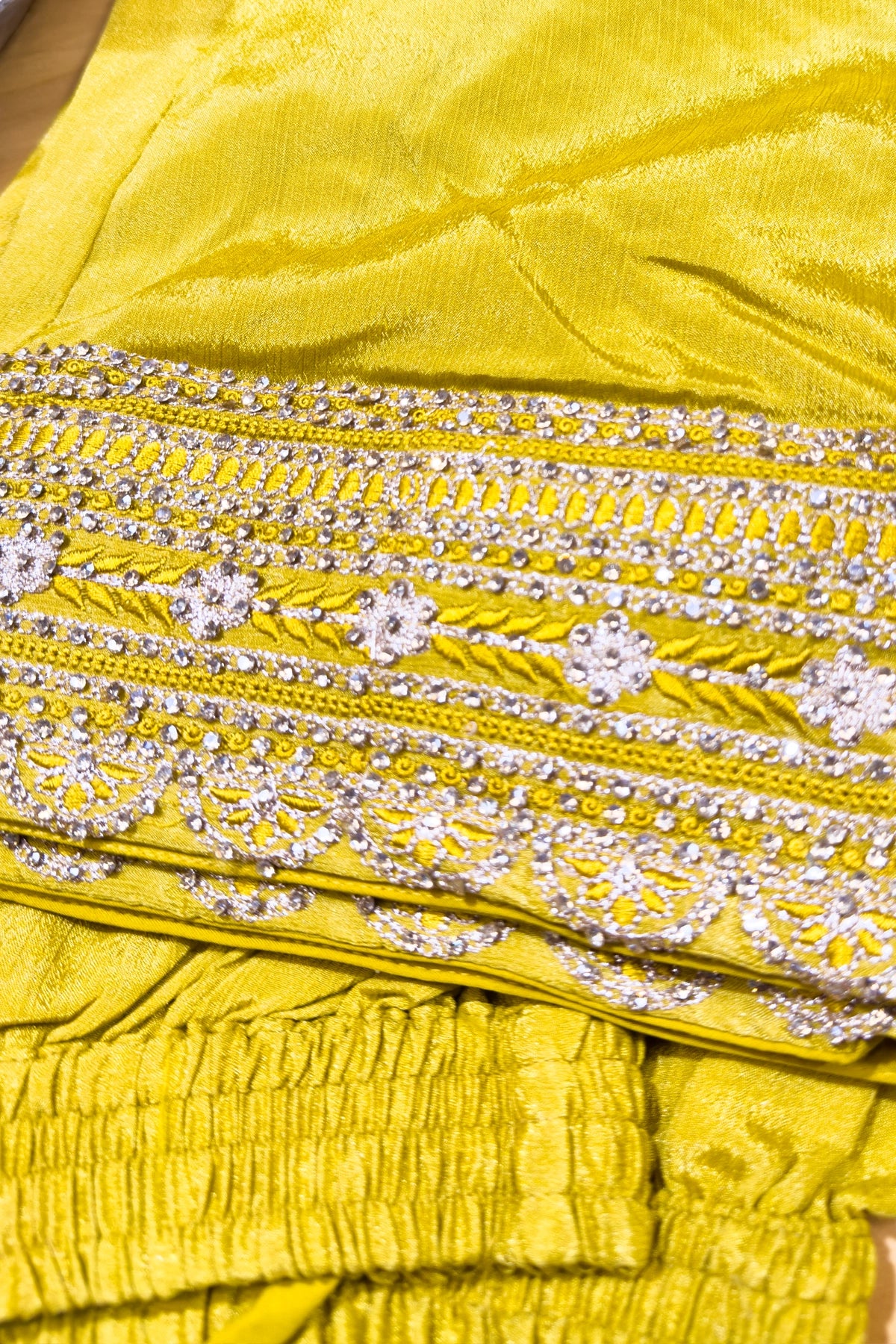 Close-up of a yellow fabric with intricate silver embroidery