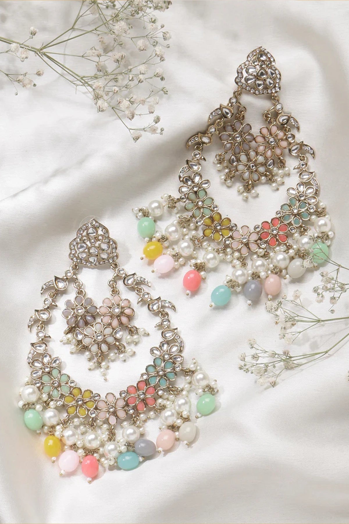 Decorative earrings with colorful beads on a white fabric background