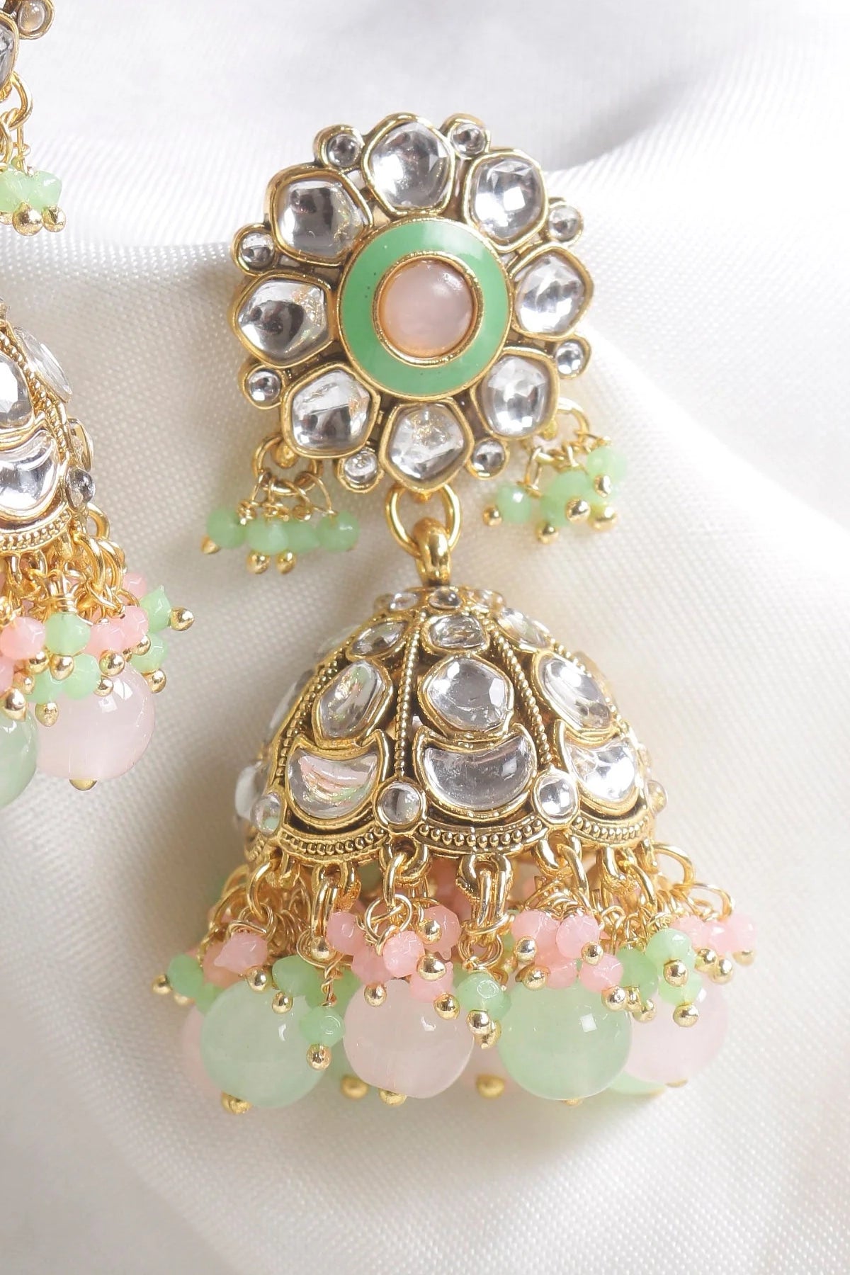 Ornate earrings with gold, silver, and pastel gemstone details on a white background