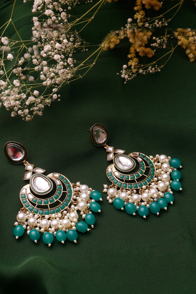 Ornate earrings with turquoise stones and pearls on a dark green background