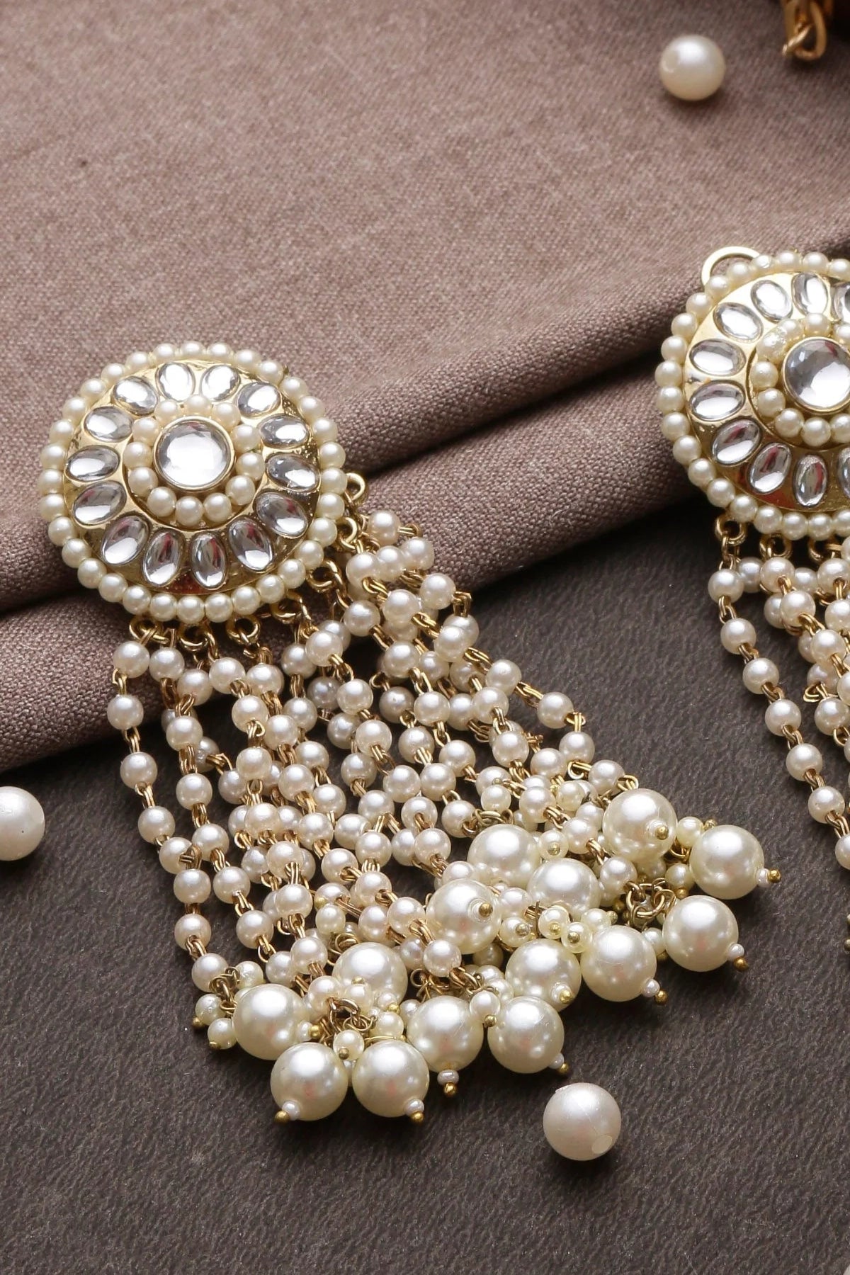 Pearl and gold earrings on a brown fabric background