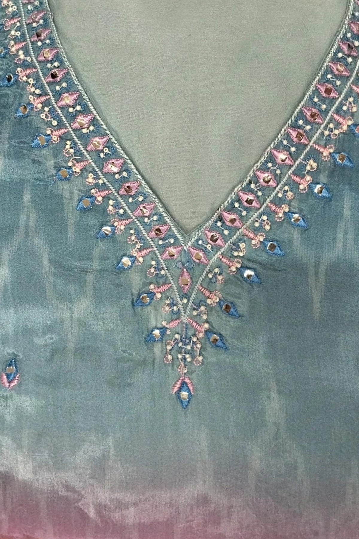 Close-up of a garment with intricate floral embroidery on a textured fabric background.