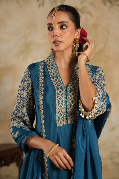 Woman wearing a blue embroidered traditional outfit with a beige backgroundWoman wearing a blue embroidered traditional outfit with a beige background