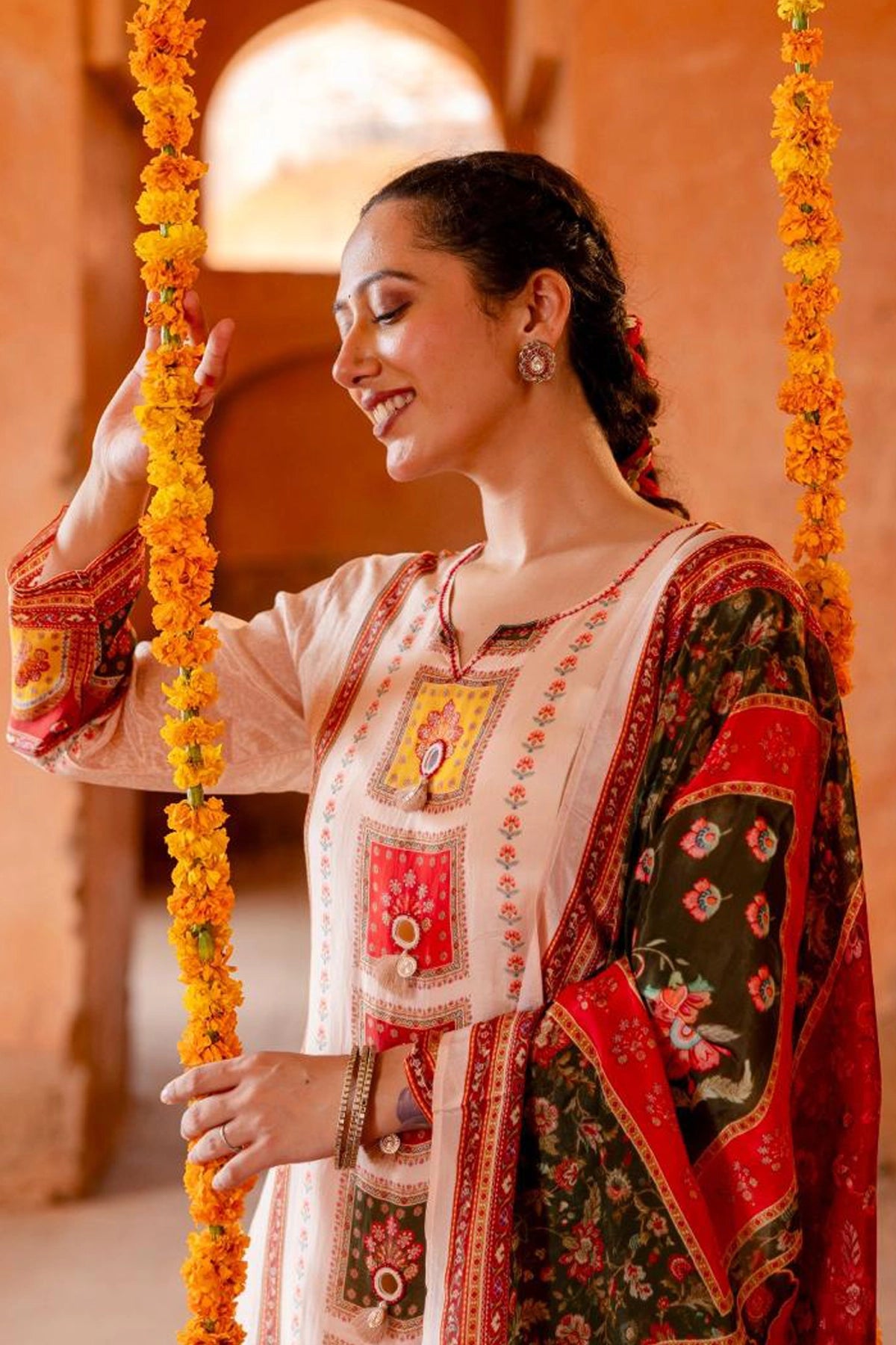 Woman in traditional embroidered outfit on a swing with floral decorations
