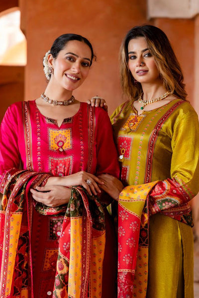 Two women in traditional pink and yellow outfits standing close together against a warm-toned background.Two women in traditional pink and yellow outfits standing close together against a warm-toned background.