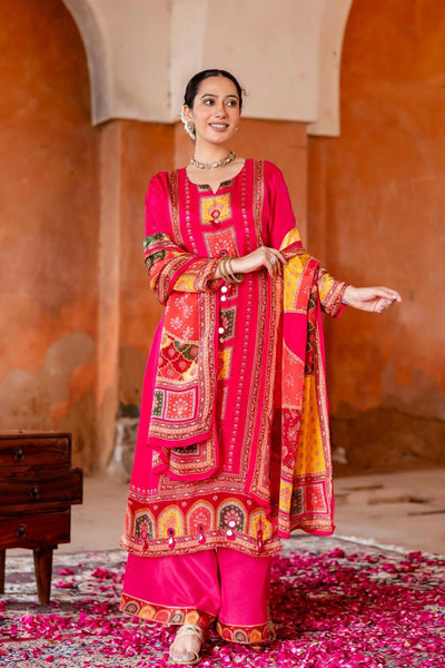 Woman in a vibrant pink traditional outfit with intricate patterns standing in a decorative setting.Woman in a vibrant pink traditional outfit with intricate patterns standing in a decorative setting.