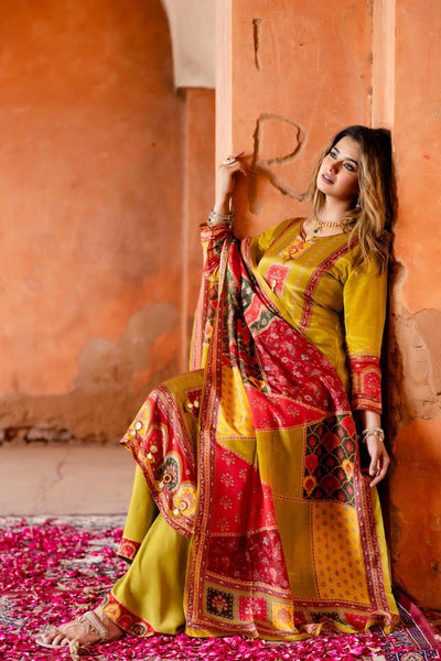 Woman in traditional yellow and red outfit standing against an orange wall with pink petals on the floor.Woman in traditional yellow and red outfit standing against an orange wall with pink petals on the floor.