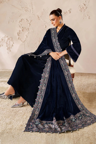 Woman wearing a navy blue dress with intricate patterns in a formal setting.