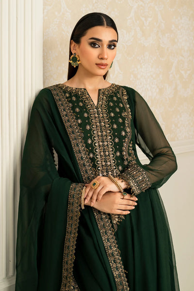 Woman wearing a dark green traditional anarkali outfit with intricate patterns against a beige wall.Woman wearing a dark green traditional anarkali outfit with intricate patterns against a beige wall.