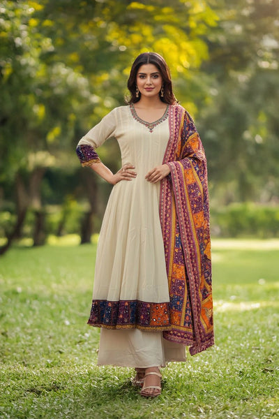 Woman in a traditional outfit with a colorful scarf standing in a park.