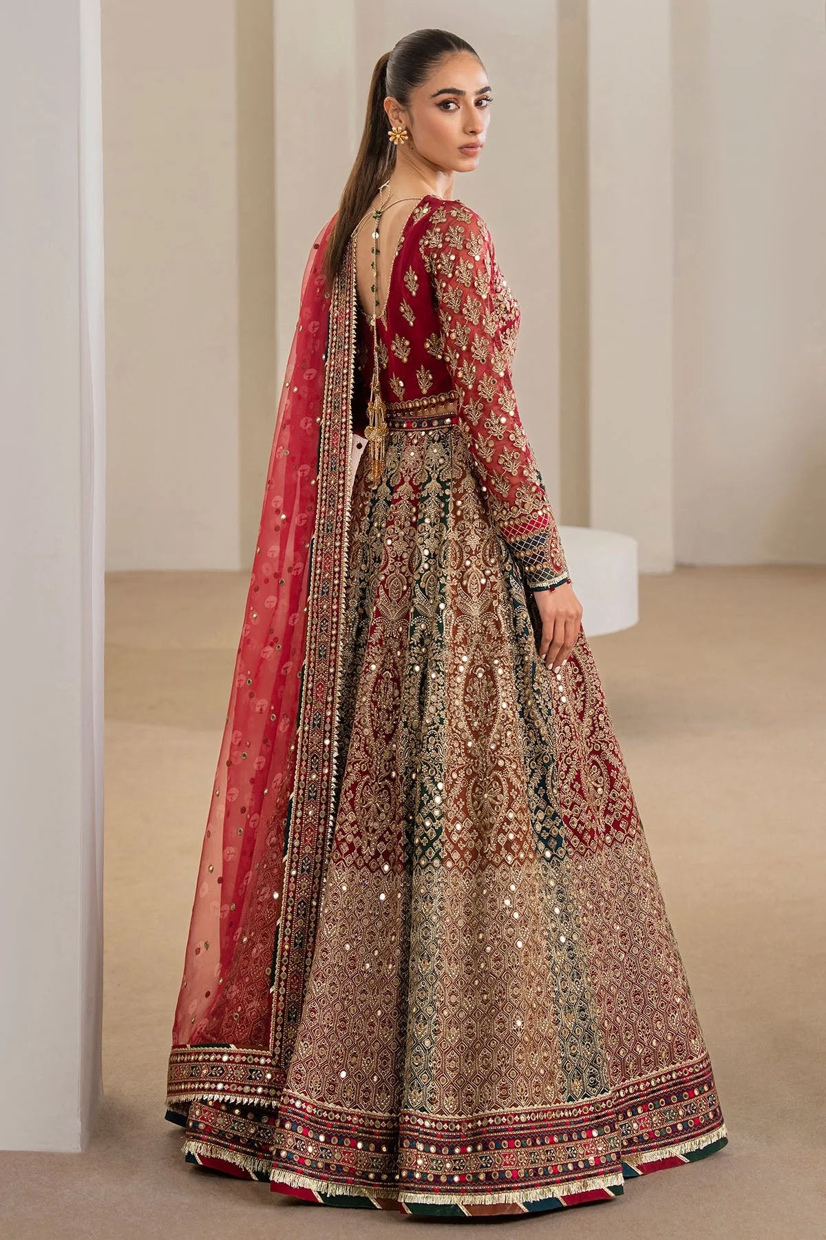 Woman wearing a traditional red embroidered Chiffon Bridal Lehenga outfit with a red dupatta in a neutral setting