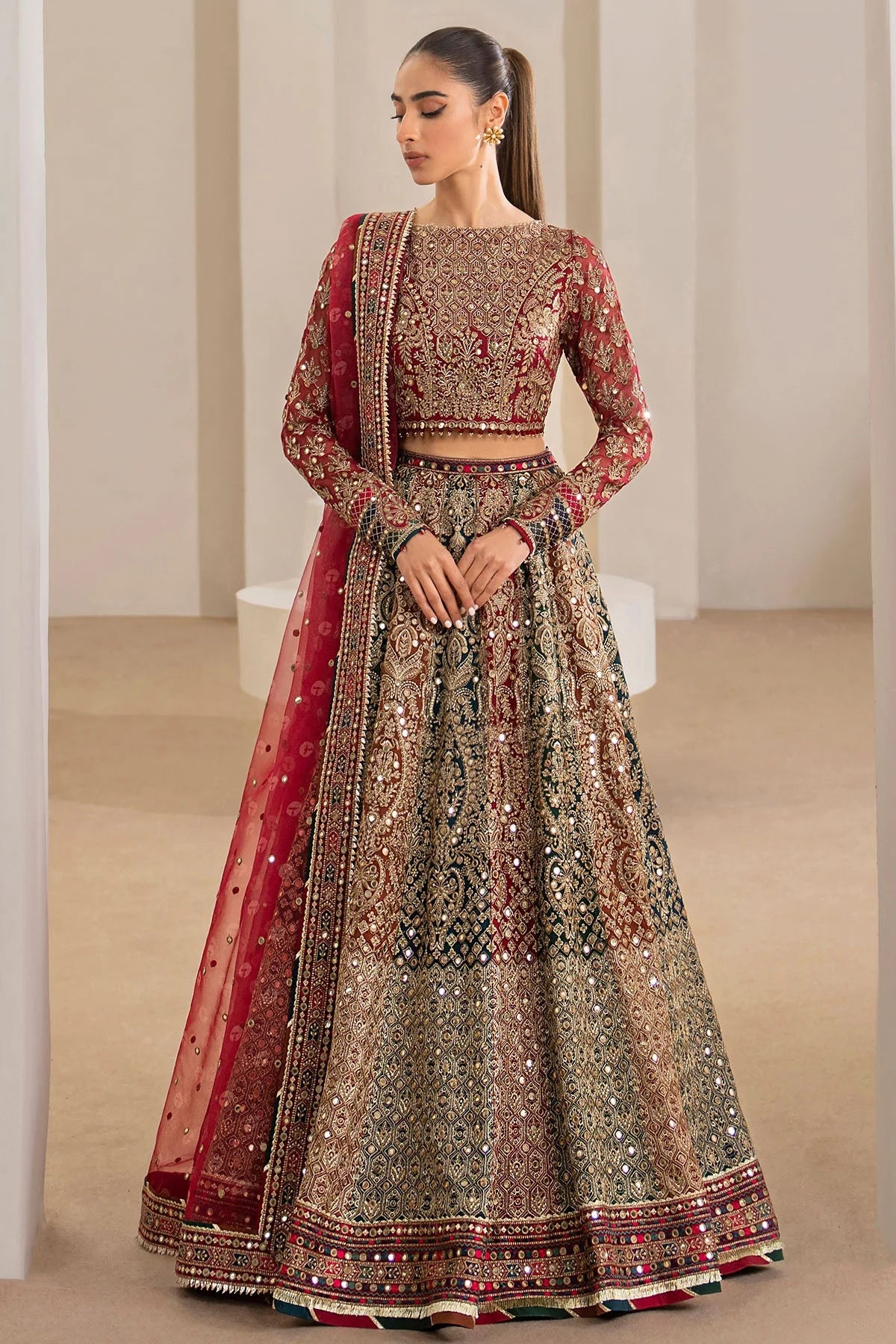 Woman wearing a traditional red embroidered Chiffon Bridal Lehenga outfit with a red dupatta in a neutral setting