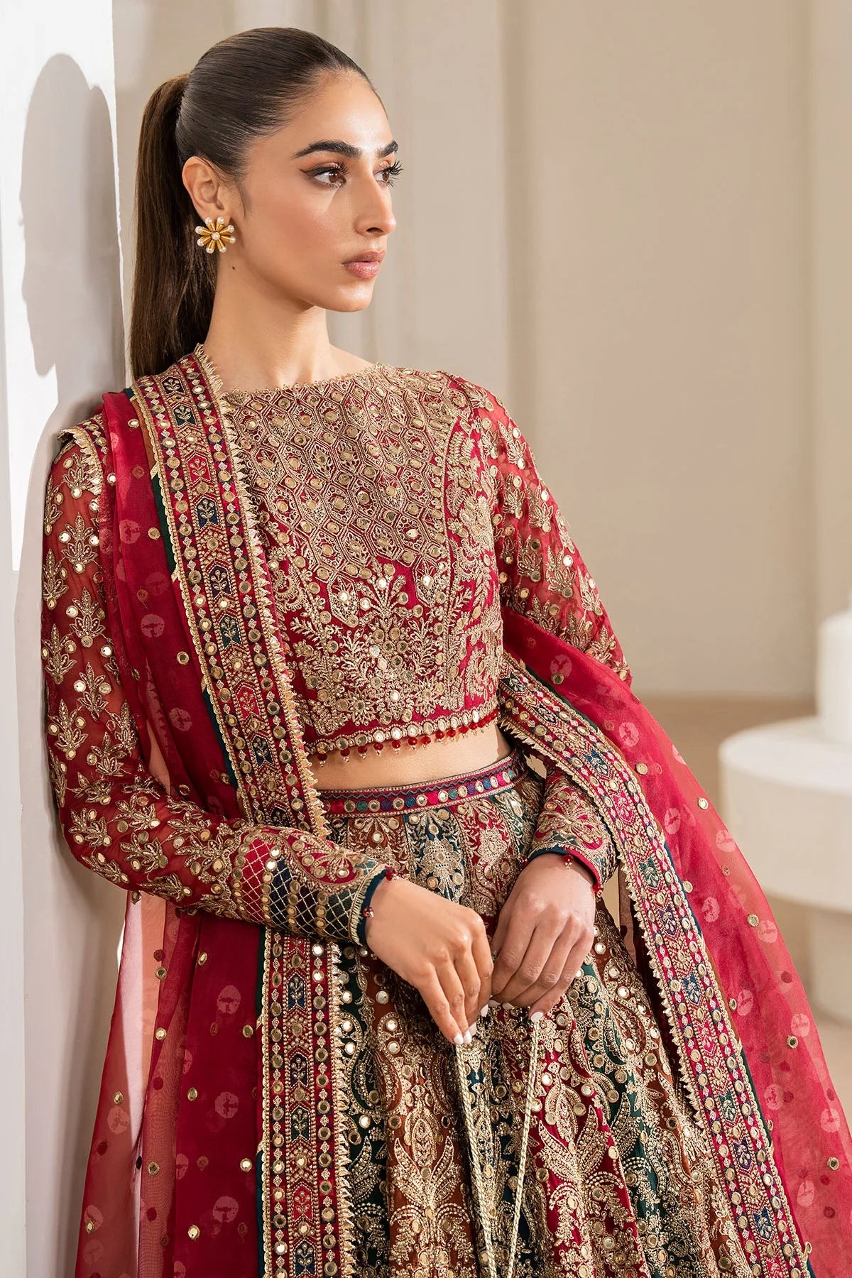 Woman wearing a traditional red embroidered Chiffon Bridal Lehenga outfit with a red dupatta in a neutral setting