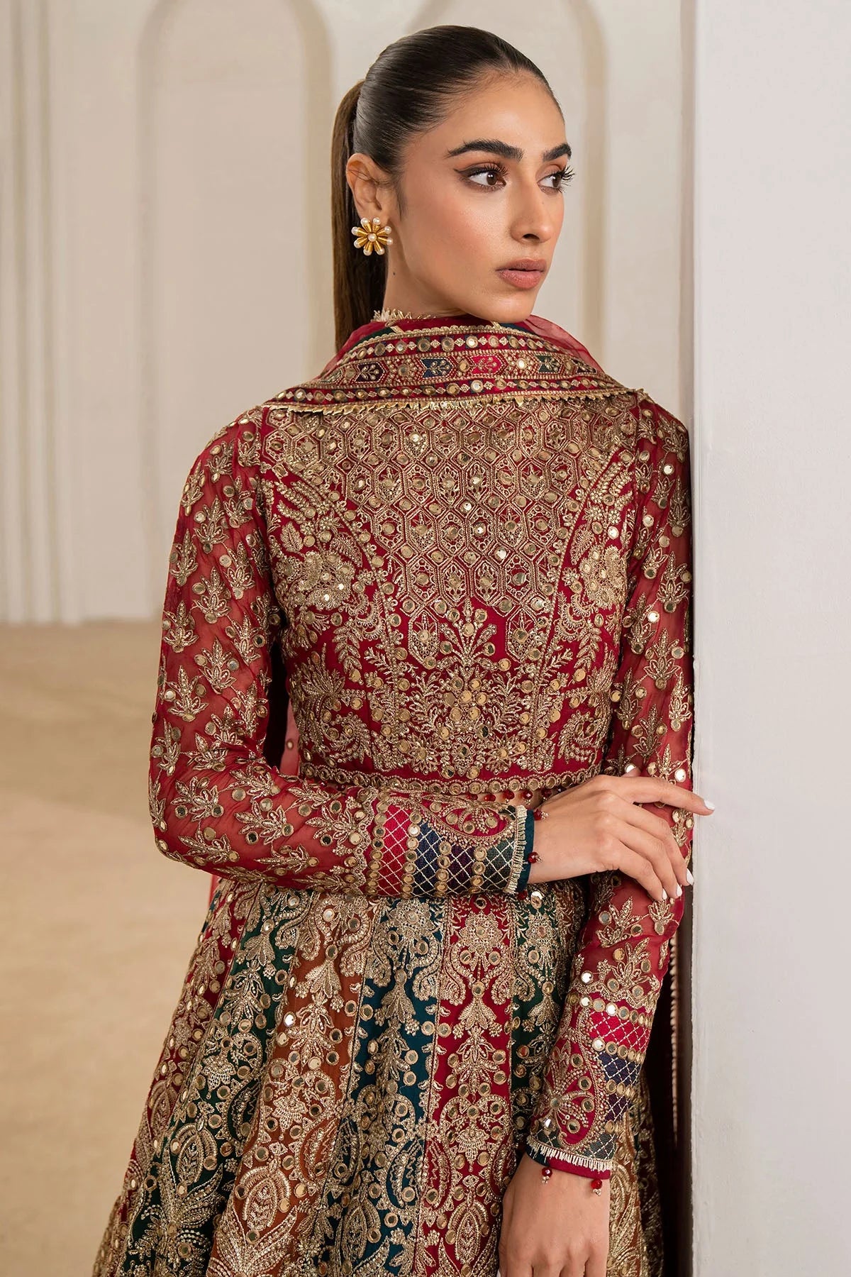 Woman wearing a traditional red embroidered Chiffon Bridal Lehenga outfit with a red dupatta in a neutral setting