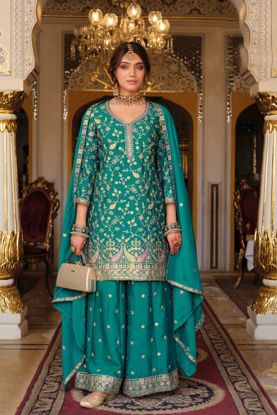 Woman in a traditional teal outfit with gold embroidery in an ornate room.Woman in a traditional teal outfit with gold embroidery in an ornate room.