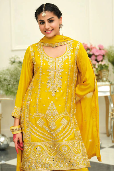 Woman in a yellow traditional sharara salwar suit outfit with intricate embroidery in an elegant indoor setting.Woman in a yellow traditional sharara salwar suit outfit with intricate embroidery in an elegant indoor setting.