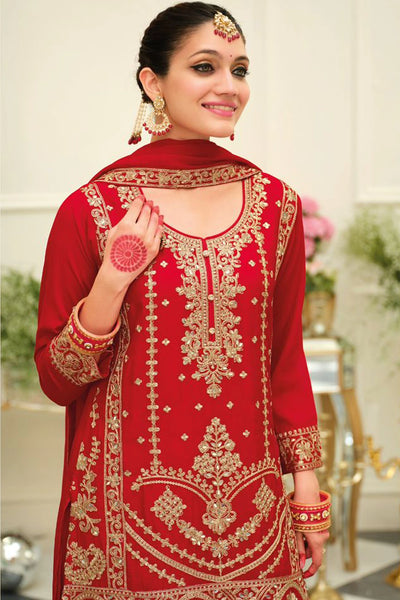 Woman wearing a red chinon silk embroidered traditional sharara outfit in an elegant indoor setting.Woman wearing a red chinon silk embroidered traditional sharara outfit in an elegant indoor setting.