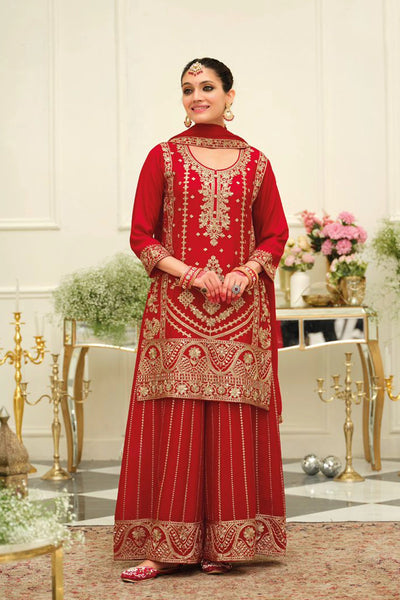 Woman wearing a red chinon silk embroidered traditional sharara outfit in an elegant indoor setting.