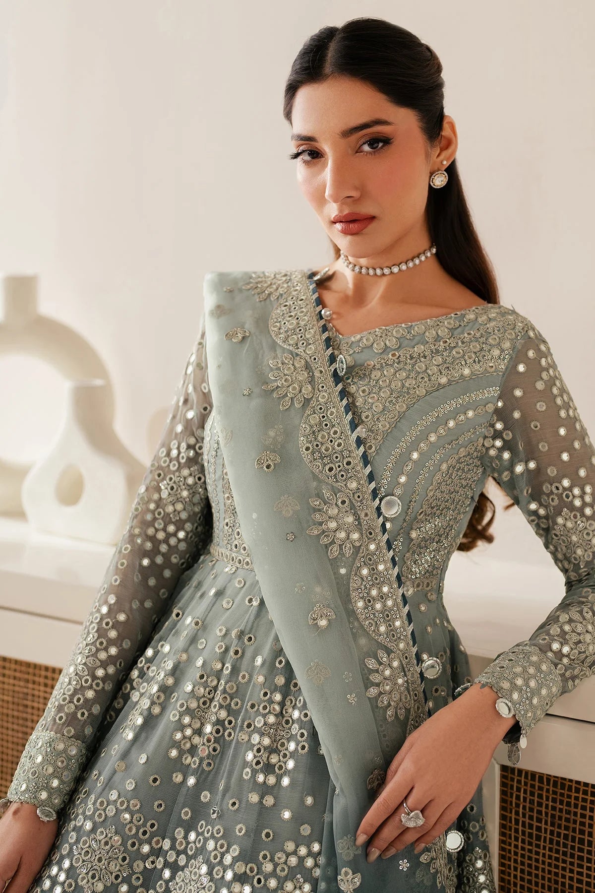 Woman wearing a light blue embroidered traditional anarkali outfit with a white background