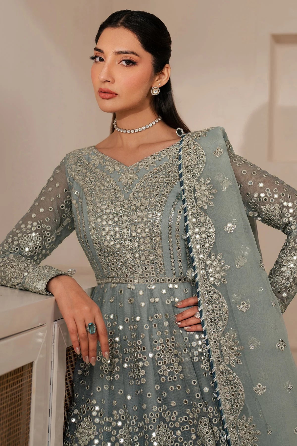 Woman wearing a light blue embroidered traditional anarkali outfit with a white background