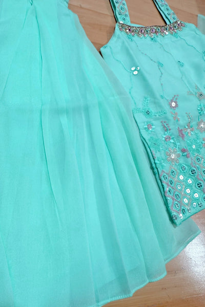 sea green girls dress with floral embroidery on a wooden surfacesea green girls dress with floral embroidery on a wooden surface